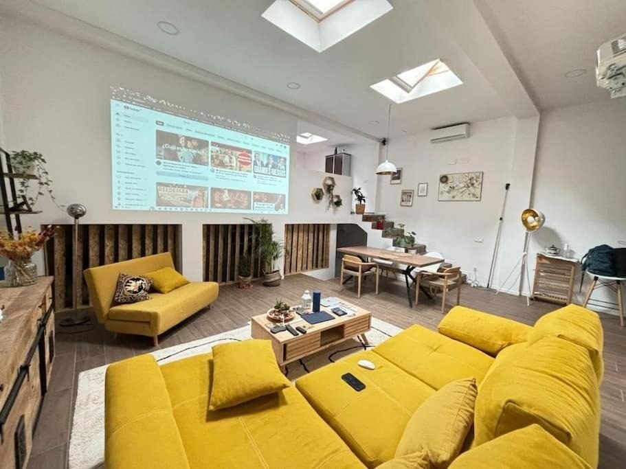Salón de doble altura con sofá amarillo y proyector